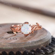 a white opal ring sitting on top of a piece of wood next to a brush