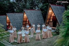 a group of women standing next to each other in front of small huts