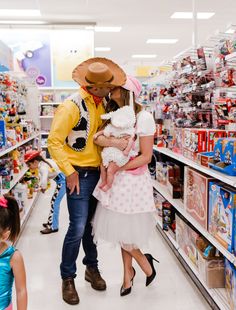 a man and woman in cowboy hats kiss as they shop for toys at a store