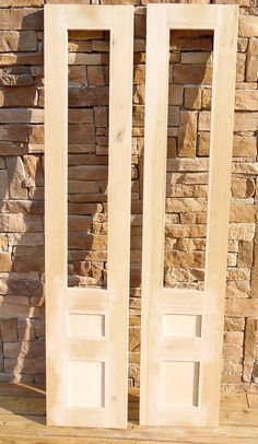 two wooden doors sitting next to each other on top of a wooden floor near a brick wall