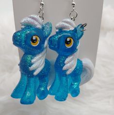 two blue and white pony earrings with glitter on them