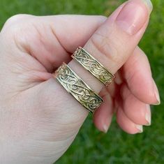 two gold rings sitting in the palm of someone's hand on some green grass