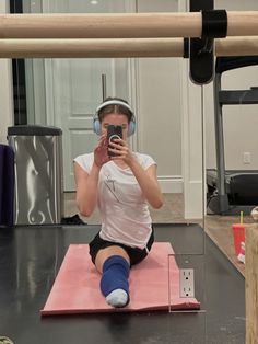 a woman taking a selfie while sitting on a yoga mat with her cell phone