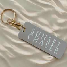 a keychain with the words sunset chaser on it sitting on a bed