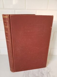 an old red book sitting on top of a white counter next to a tiled wall