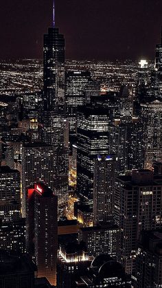 an aerial view of the city at night with skyscrapers lit up in red and blue