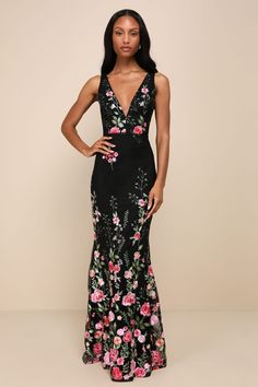 a woman in a black and pink floral print gown with her hands on her hips