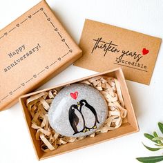 two rocks with penguins on them are in a box and one has a happy anniversary message