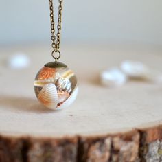 a small glass ball with shells inside on a chain