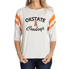 Elevate the style of your game day tee with this Oklahoma State Cowboys Sabrina Jersey T-shirt. It features the team name and logo accentuated by contrast-color side stitching and sleeve stripes. A rounded hem gives this Oklahoma State Cowboys shirt a more comfortable fit and feel. Varsity Logo Print T-shirt For Game Day, Sporty College T-shirt With Team Logo, Collegiate Game Day T-shirt With Team Name, Casual Jersey T-shirt For Game Day, Varsity Jersey Tops For Fan Gear, Varsity T-shirt With Team Name For College, Collegiate Graphic Print Top For Game Day, Varsity Logo Print Top For Game Day, Varsity Tops With Logo Print For Game Day