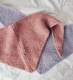 two knitted scarves laying on top of each other, one pink and the other blue