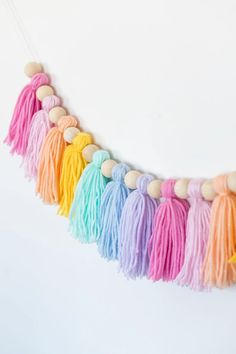 multicolored tasselled garland with wooden beads hanging from the side on a white wall