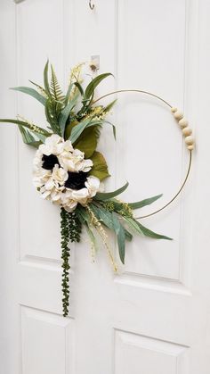 a wreath with flowers and greenery hanging on a door