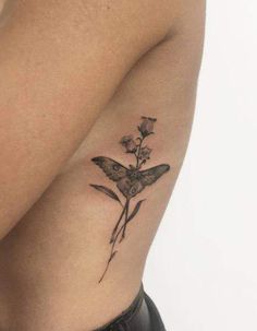 a small tattoo on the back of a woman's shoulder with a butterfly and flower