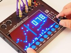 a person using an electronic device to play the game pac - man on a white table