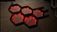 four hexagons with red lights on them sitting on a bed