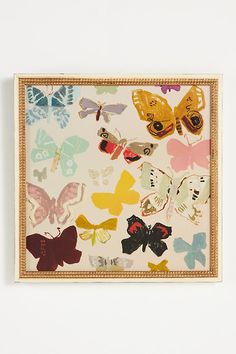 a painting with many different colored butterflies on it's frame, hanging on the wall