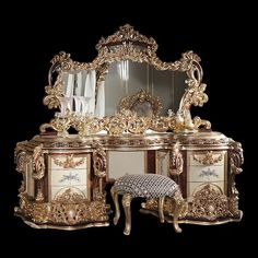 an ornately decorated dressing table with mirror and stool in gold leafed finish, against a black background