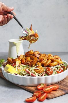 the shrimp salad is being lifted with a fork by someone holding a spoon over it