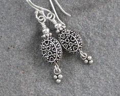 "Oxidized Turkish sterling silver oval beads are accented with coordinating sterling silver charms and securely wire wrapped to sterling silver ear wires. These dainty Bali style earrings are sweet and unique. Perfect to wear everyday. Oxidation may vary slightly for each bead. Total length from the top of the ear wires measures 1 1/2\". Sterling silver is .925 pure silver. Turkish silver is .925 pure silver. Bali silver is .925 pure silver. Check out other items in my shop here: https://www.ets Silver Oval Wire Wrapped Earrings, Oval Silver Wire Wrapped Earrings, Artisan Silver Earrings With Round Beads, Silver Bead Artisan Earrings, Silver Oval Beads For Jewelry Making, Artisan Silver Earrings With Silver Beads, Sterling Silver Teardrop Earrings With Silver Beads, Sterling Silver Oval Pendant Earrings In Silver, Sterling Silver Jewelry With Oval Beads For Gifts