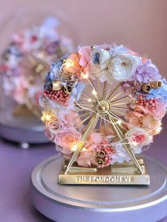 a ferris wheel decorated with flowers and lights on top of a purple table next to other items