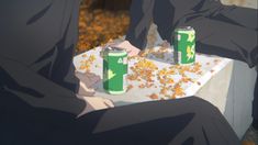 two people sitting at a table with cans of soda and popcorn in front of them