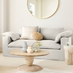 a living room filled with furniture and a round mirror