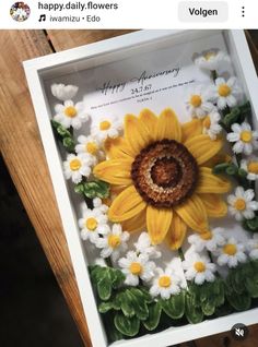 a sunflower in a white box with flowers around it