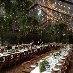 an outdoor dining area with tables, chairs and lights hanging from the ceiling over them