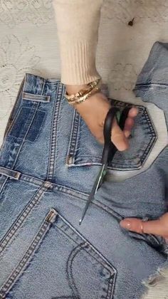 someone is cutting off their jeans with scissors