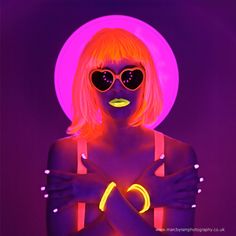 a woman with neon makeup and sunglasses on her face is standing in front of a purple background