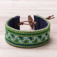 Featuring green cross-stitched patterns in the style of Hmong hill tribe handicrafts this cotton wristband bracelet from Thailand is designed by Nulee. She completes the bracelet with leather cord and an adjustable raintree wood button clasp. Hmong Embroidery, Embroidered Bracelet, Silver Bands, Jewelry Gallery, Hand Painted Jewelry, Wristband Bracelet, Green Jewelry, Shopping Ideas, Bead Jewelry