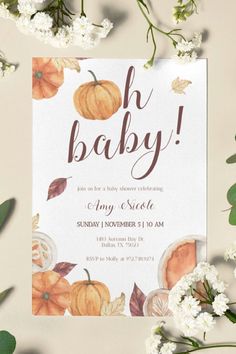 an autumn baby shower with pumpkins and leaves on the bottom, in front of white flowers