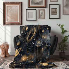 an image of a space themed blanket on a chair in front of some framed pictures