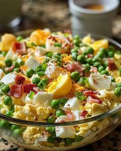 a glass bowl filled with eggs, peas and bacon