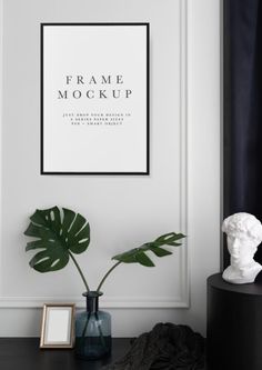 a black table with a vase and a plant on it next to a white wall