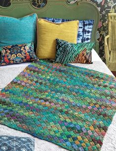 a bed topped with lots of pillows next to a green headboard and foot board