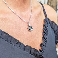 a woman wearing a necklace with a rose charm on it's neck and a chain around her neck