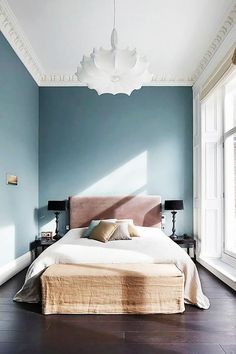 a bedroom with blue walls and white trim, hardwood flooring and a large bed