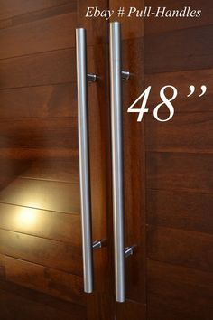 two stainless steel door handles are shown in front of a wood paneled wall with the numbers 24 - 29