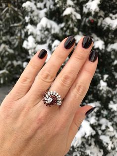 Dramatic swirls of synthetic rubies and diamonds accent this 1970s cocktail ring. A fabulous 18k white gold ring is adorned with 22 faceted synthetic rubies and 23 round brilliant diamonds. The top of the ring measures 0.7 inches from top to bottom by 0.85 inches wide. The interior of the band is marked for 18k gold. The center diamond measures 0.20 carat with G-H color, SI3 clarity, and there are 22 side diamonds. The total carat weight of all diamonds is 0.86ct. The ring is currently a size 7 Ruby Ring Vintage, Rubies And Diamonds, Diamond Ring Vintage, Ruby Diamond Ring, Vintage Cocktail Ring, Diamond Cocktail Ring, Ruby Diamond Rings, Diamond Cocktail Rings, 18k Gold Ring