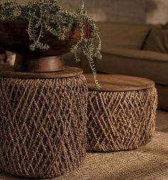 two woven stools with plants in them on the floor next to a brown couch