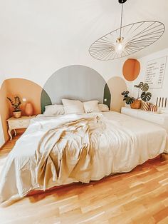 a large bed sitting in the middle of a bedroom next to a wooden floor and white walls