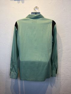 "1950s vintage reproduction Hollywood Rogue two tone mint green and black shirt The shirt has a two tone design with mint green and contrasting black on shoulders and neckline. The garment has a loop collar, five button down front, one patch pocket and long sleeves. The label reads \"Hollywood Rogue\" and the shirt is in new unworn condition. As with all clothes made by \"Hollywood Rogue\" this shirt was made in an original 1950's design and is only available in very limited numbers. Made in Cal Classic Green Johnny Collar Tops, Retro Black Long Sleeve Shirt, Retro Black Tops For Work, Retro Green Button-up Top, Retro Green Collared Shirt, Retro Black Workwear Shirt, Retro Black Shirt For Work, Vintage Black Workwear Shirt, Vintage Black Shirt For Work