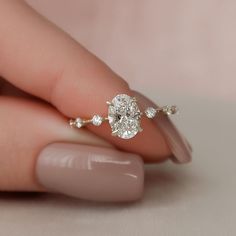 a woman's hand holding a diamond ring on top of her finger, with the setting in white gold