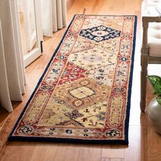 a large rug is on the floor next to a chair and vase with flowers in it