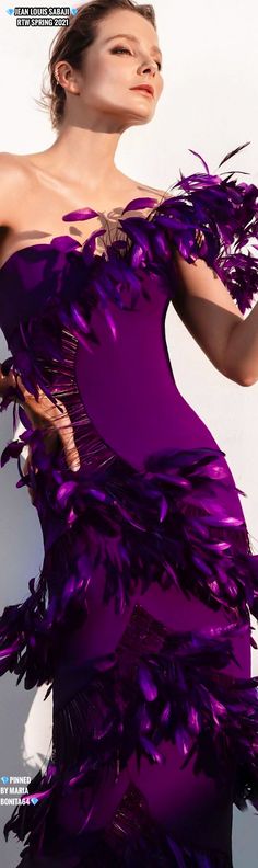 a woman in a purple dress with feathers on it