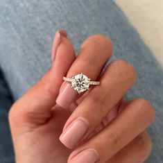 a woman's hand holding a ring with a diamond on it and the middle finger