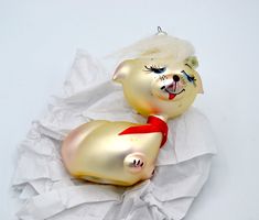 two glass pigs with white hair and red bows on their heads sitting on some paper