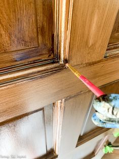 a red toothbrush sticking out of the side of a wooden door with woodgrains